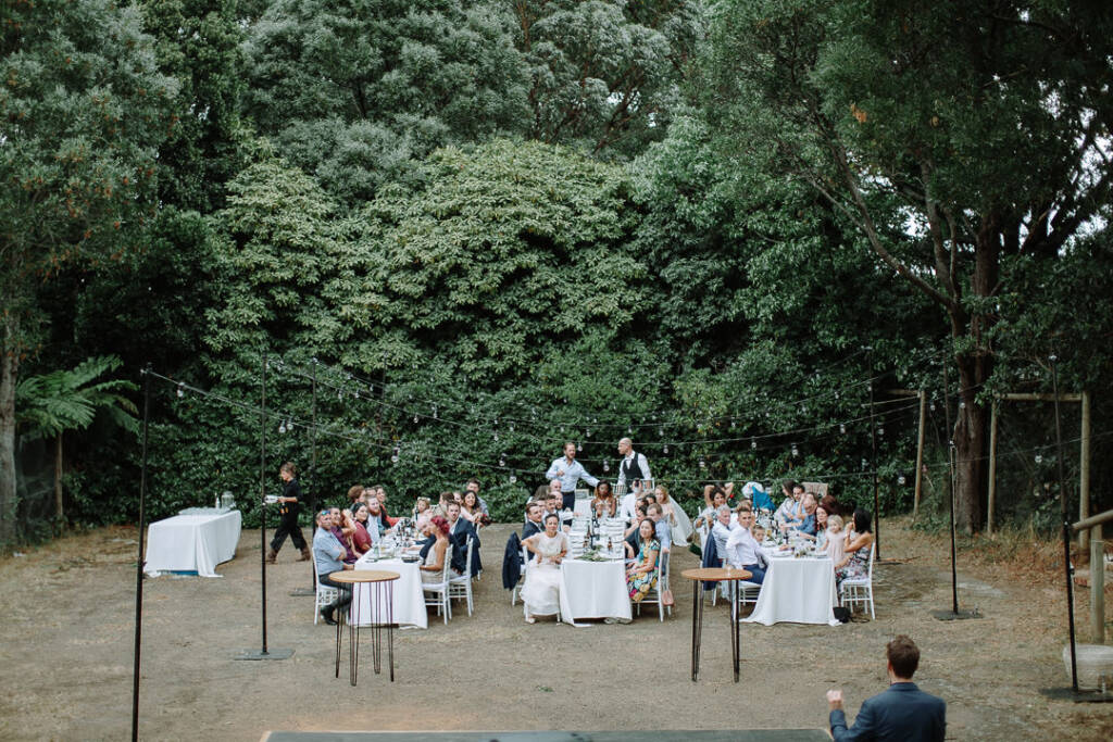 Guests gather around long outdoor tables at Strathvea beneath the trees.