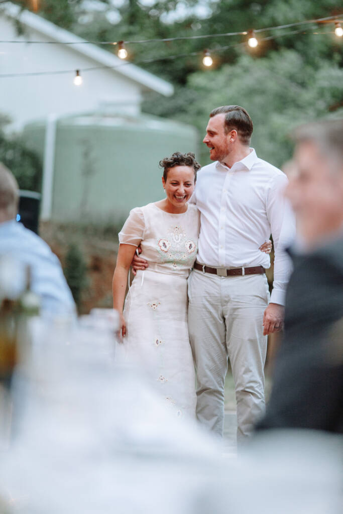 Sarah and Jye stand with their arms around each other during the reception.