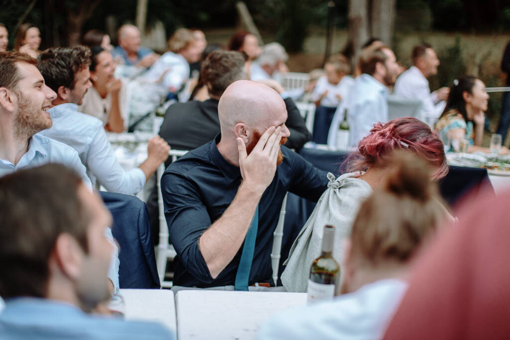 A guest covers part of their face while listening to the reception speech.