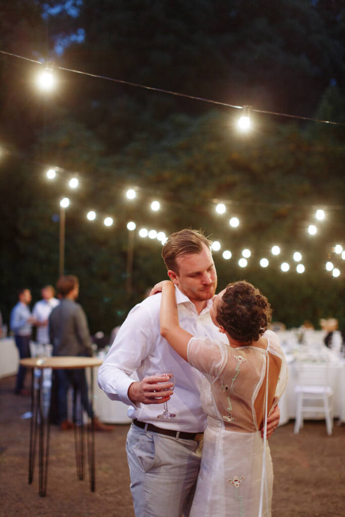 Sarah puts her arms around Jye as they dance beneath festoon lights at Strathvea Guesthouse.