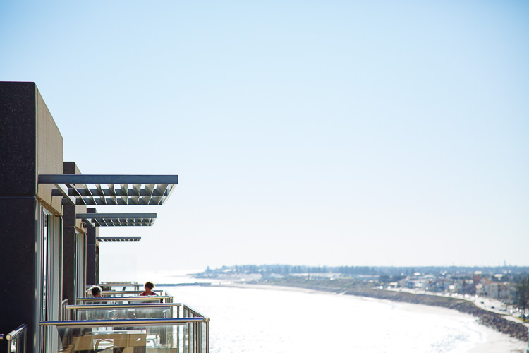A coastal view looks past glass balconies towards the beach and sea.