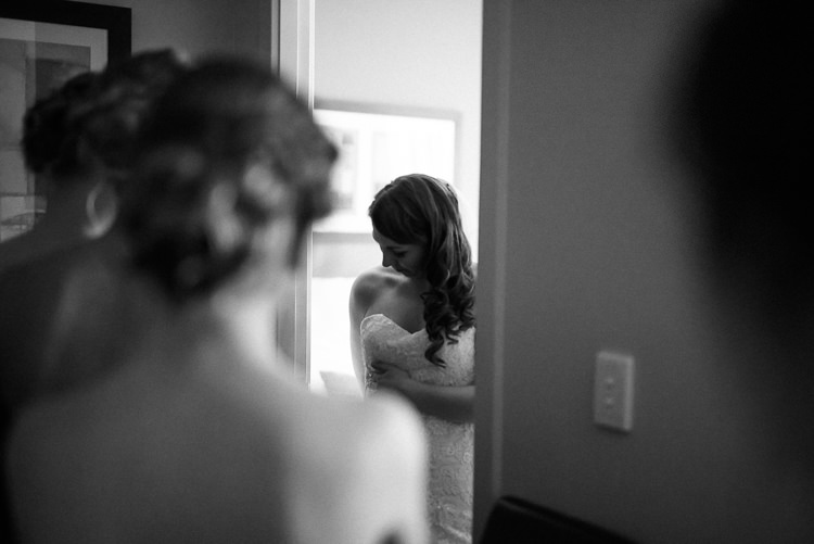 Black-and-white photo of Shannon looking down at her lace bodice through a doorway.