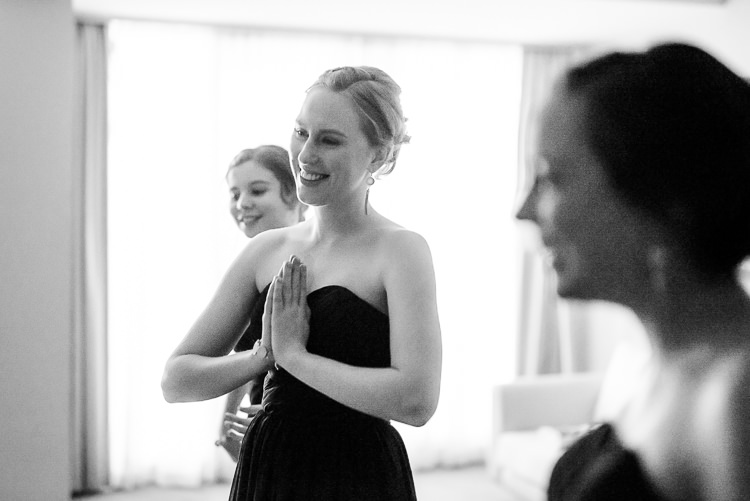 Black and white of a bridesmaid in strapless navy pressing her hands together and smiling.