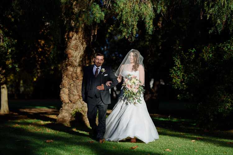 Shannon walks arm-in-arm with a grey-suited man across the lawn at Sunnybrae Estate.