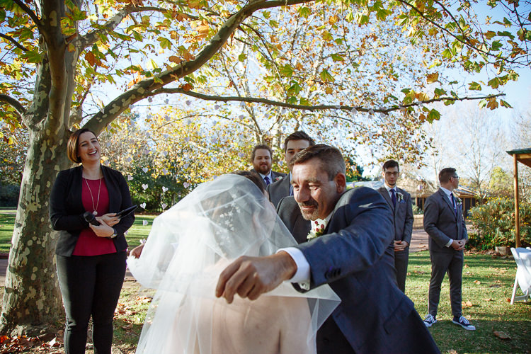 The man with the moustache lifts Shannon's veil as the celebrant in black and red laughs.