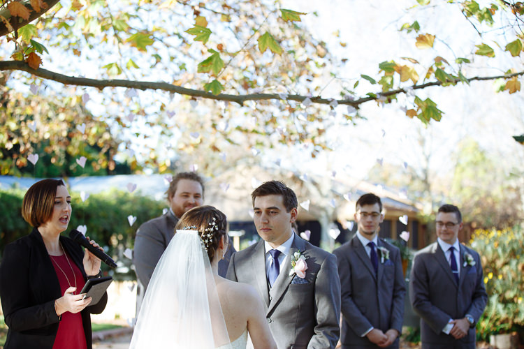 Shannon and Luke face each other during their garden wedding ceremony at Sunnybrae Estate.