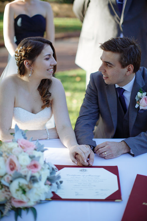 Shannon and Luke hold hands beside their marriage certificate at Sunnybrae.