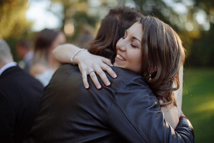 Shannon smiles with eyes closed as she hugs a woman in a black leather jacket.