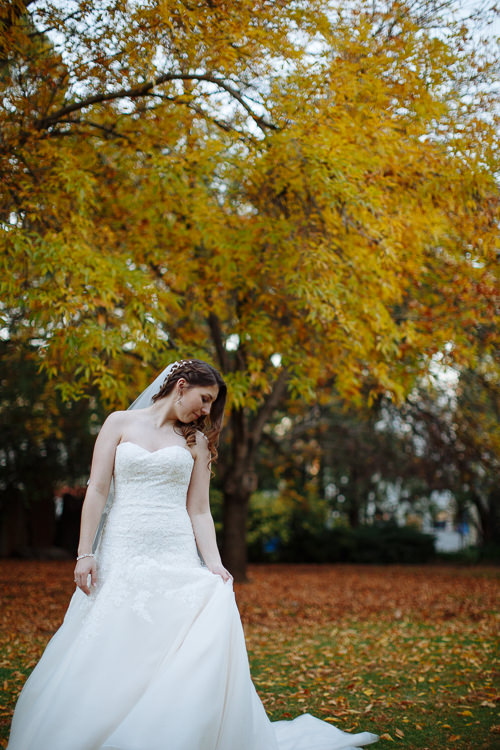 Shannon looks down at her gown beneath yellow leaves at Sunnybrae.
