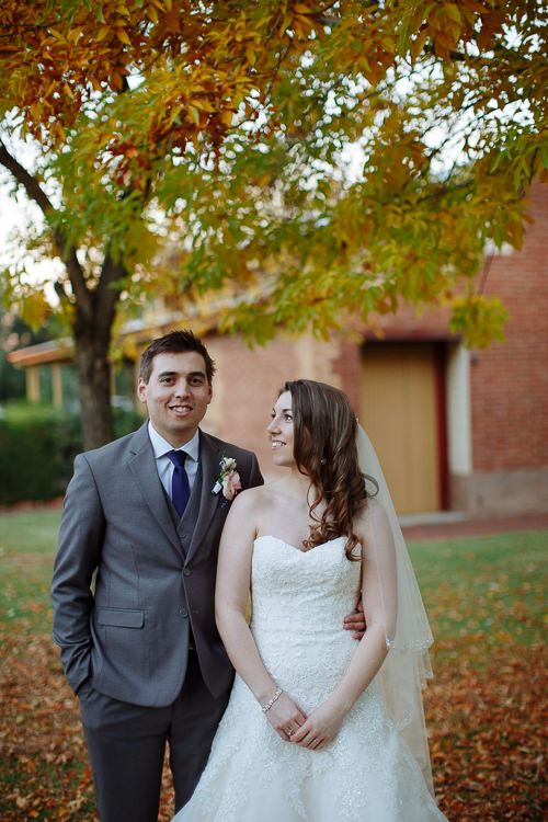 Shannon and Luke pose beneath yellow leaves beside a red-brick building at Sunnybrae.
