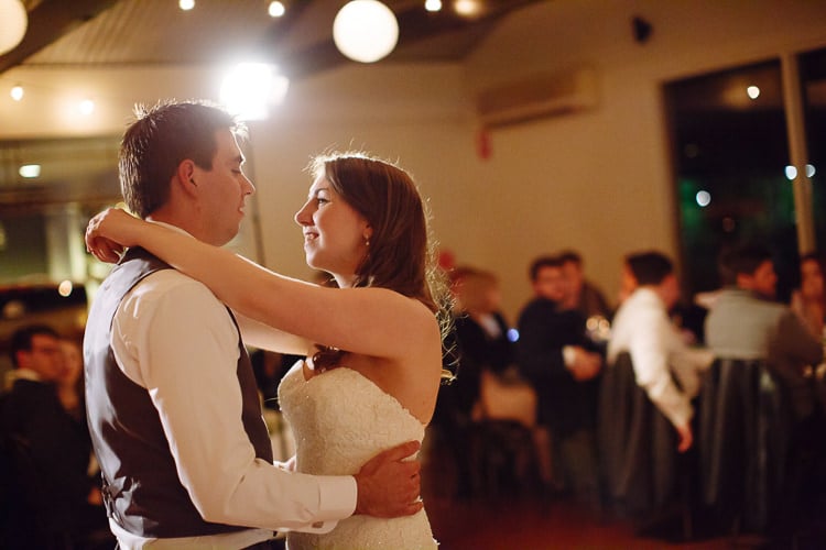 Shannon and Luke smile at each other while dancing before guests at Sunnybrae Estate.
