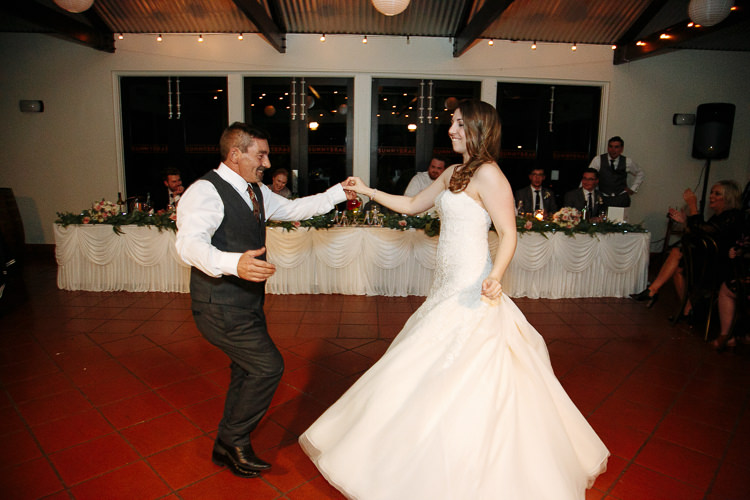 The bride dances with a guest on the tiled floor at Sunnybrae Estate.