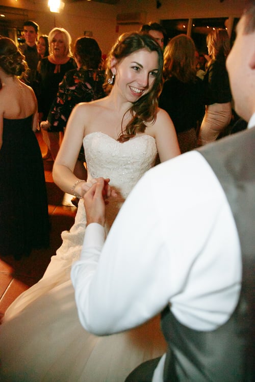 Shannon smiles while holding Luke's hand on the tiled dance floor at Sunnybrae Estate.