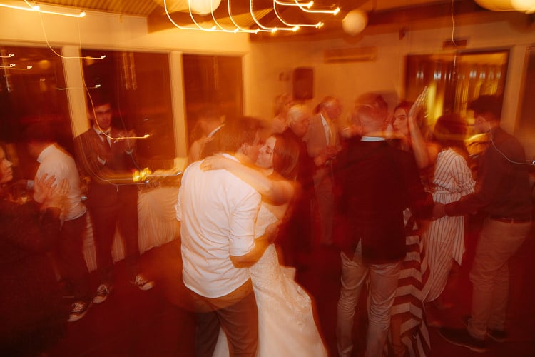 Shannon and Luke embrace among guests in a motion-blurred dance photo at Sunnybrae.