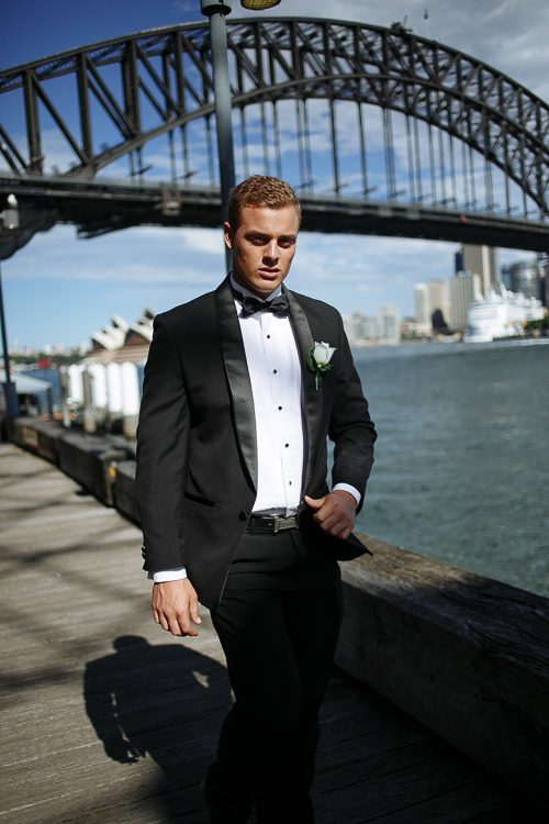 A man walks a Sydney Harbour timber boardwalk beneath the Harbour Bridge.