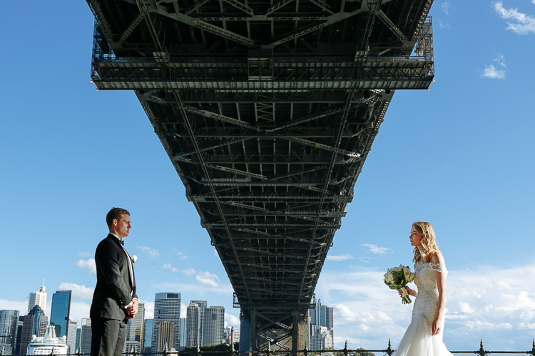 The couple face each other on the Sydney Harbour foreshore beneath the Bridge deck.