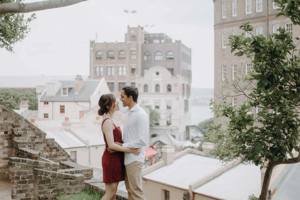 Foreheads nearly touching, Jeannette and Pierre stand above the heritage rooftops of The Rocks.