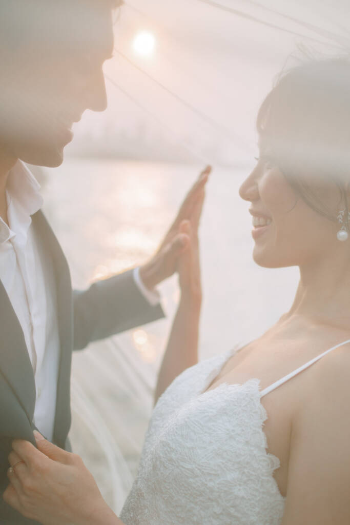 Through a veil at Bradleys Head, Jeannette and Pierre smile at each other with sunlight on the harbour behind.