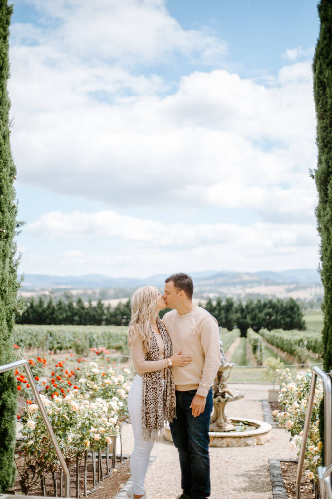 Danni and Jarrod kiss between Tokar Estate's cypress trees above the rose garden.
