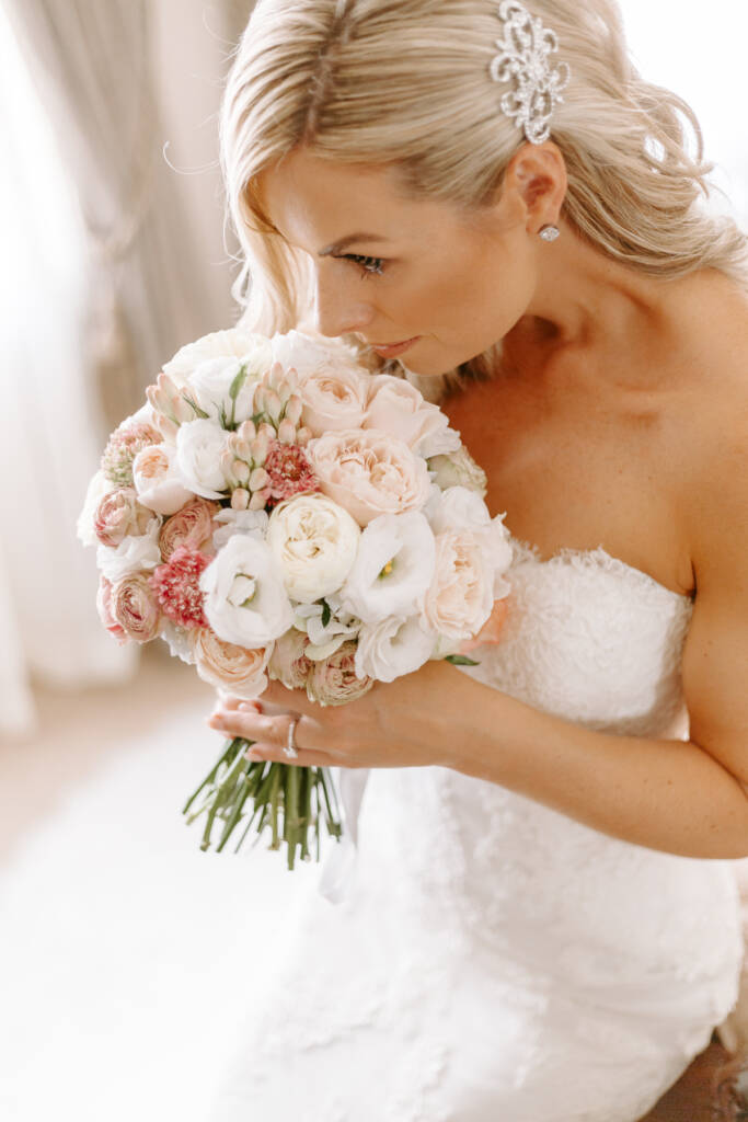 The bride breathes in the bouquet from above, crystal comb glinting in her hair.
