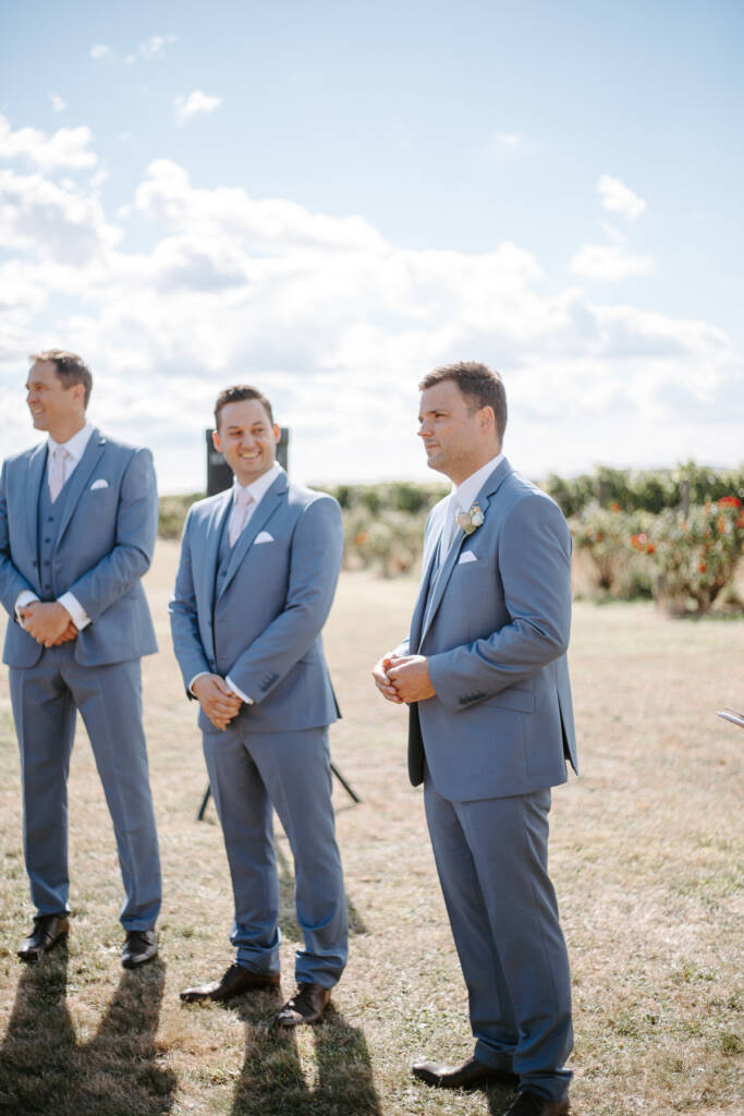 Jarrod waits with two groomsmen in powder-blue suits and pale-pink ties.