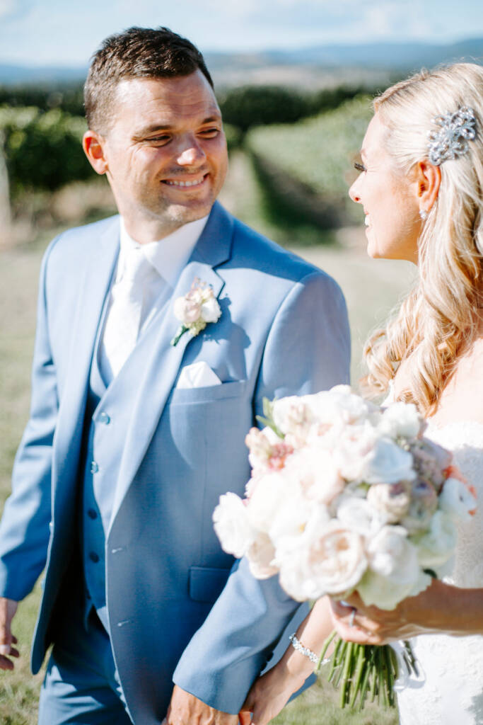 A grin passes between the bride and groom over the armful of garden roses and ranunculus.