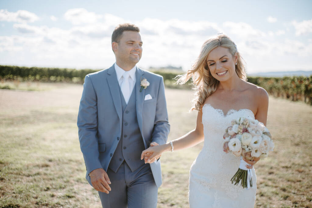 The groom's attention drifts sideways as the bride laughs at the bouquet.