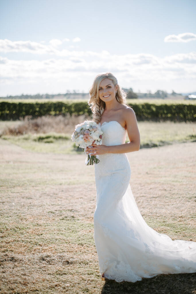 Danni poses full-length in her lace gown, curls loose over one shoulder.