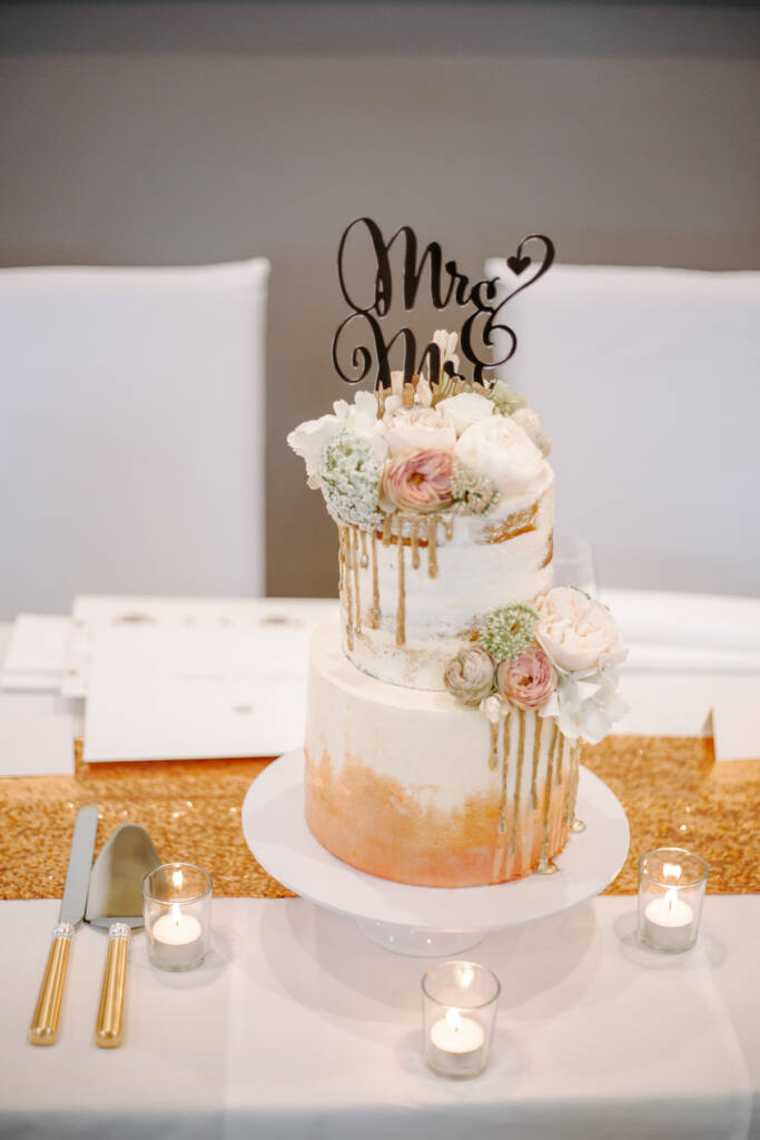 A gold-drip wedding cake and blush flowers on a Tokar Estate reception table.