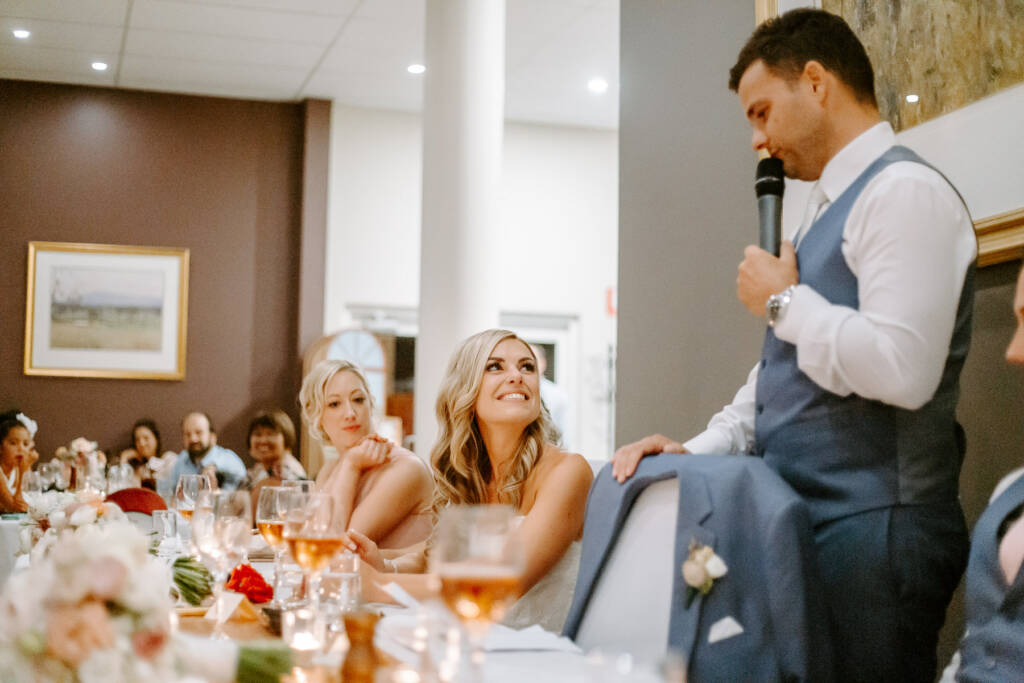 The bride looks up mid laugh as the groom takes his turn to speak.