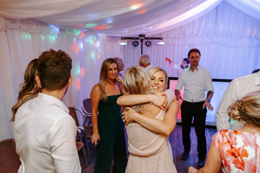 A tight hug between songs, bracelet sparkling on the bride's wrist.