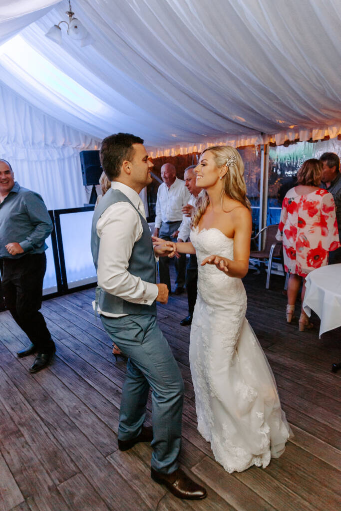 Danni and Jarrod face each other while dancing under the marquee.