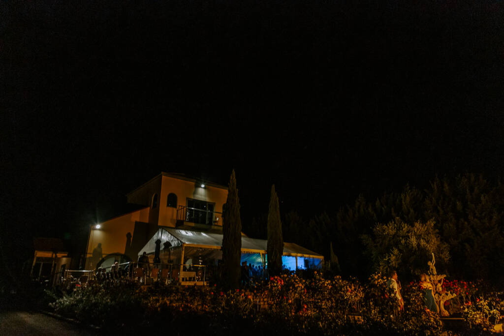 Tokar Estate Winery's building and marquee glow above the rose garden at night.