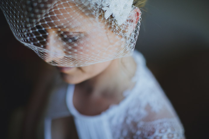 Eyes lowered beneath the crosshatch of the birdcage veil