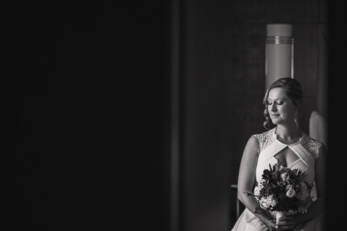 A monochrome pause by the column lamp, bouquet held low