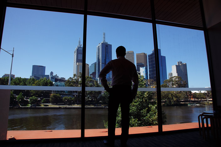 Silhouetted against the glass, Dennis surveys the river and the city towers.
