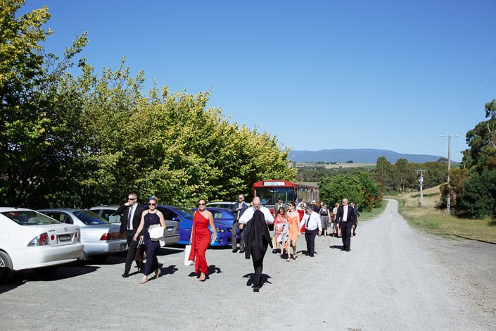 Guests stream from the red bus up the gravel farm track