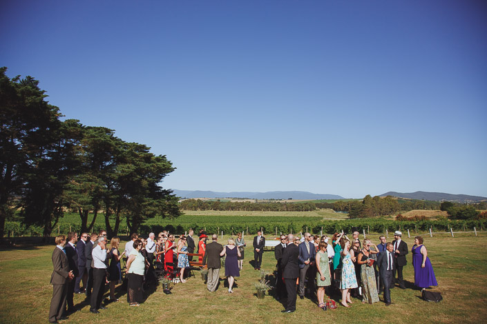 The congregation gathers on the grass beneath a huge blue sky