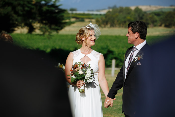 A look between Lindsey and Dennis over the harvest bouquet, vines rolling behind.