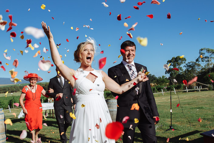 An arm shoots up through a storm of rose petals