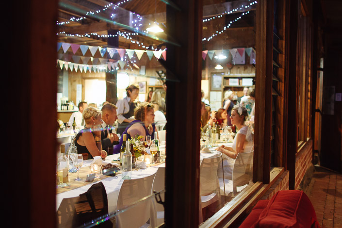 Through the window glass, candlelight carries the dinner conversation