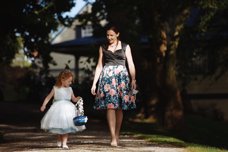 A flower girl carries a decorated basket beside a woman along the garden path at Yester Grange