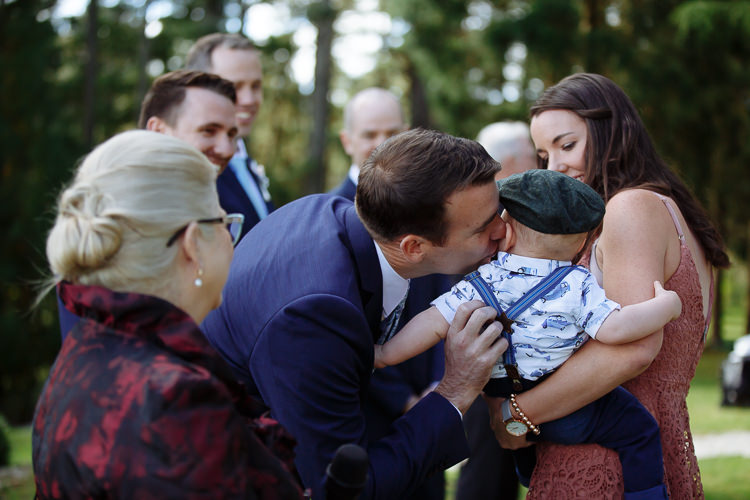 Russell leans to kiss a baby held by a guest before the ceremony