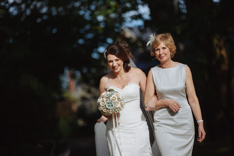 Heidi walks arm in arm with an older woman while holding her wedding bouquet