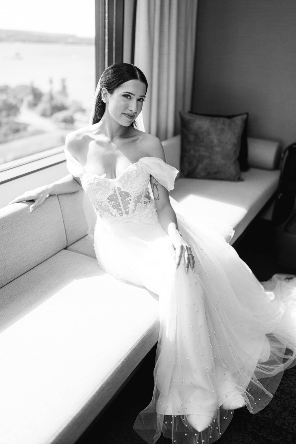 The bride seated in window light at Burnt Orange, Mosman, Sydney Harbour beyond