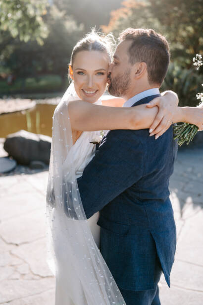 A kiss on the cheek and a pearl-studded veil beside the pond in Fitzroy Gardens