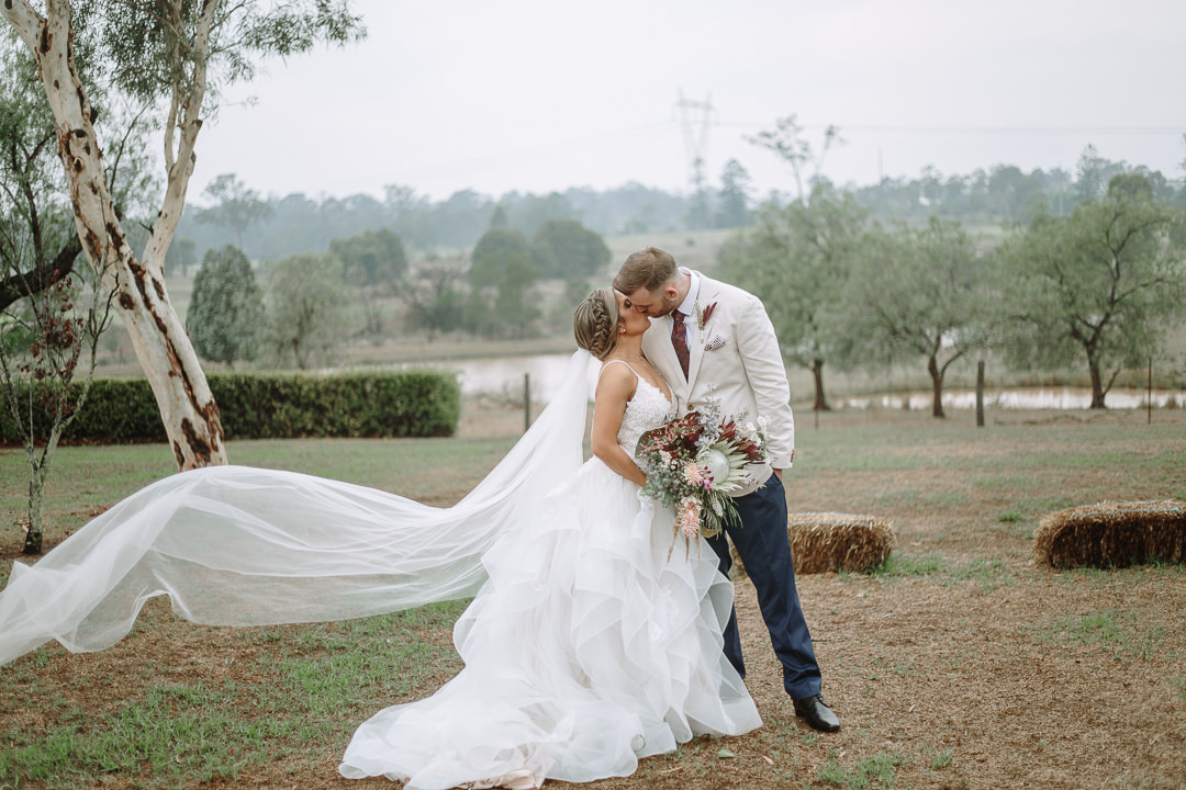 A kiss under the ghost gum between the hay bales at Gledswood Homestead