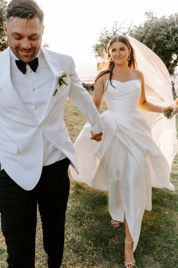 Walking hand in hand with the veil lifting, groom in a white dinner jacket &mdash; Harbour Room RMYS, St Kilda