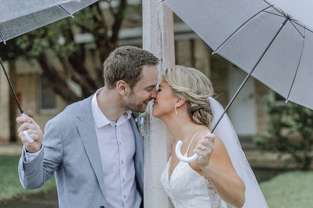 Nose to nose under clear umbrellas in the Manly rain, Maddy and Monty