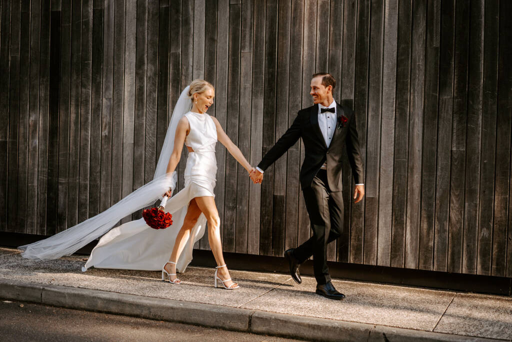 Laura and Oscar mid-stride past the timber facade at Sergeants Mess, Mosman